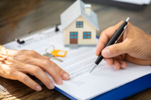 close-up of a real estate agent's hand helping client in filling contract form over desk